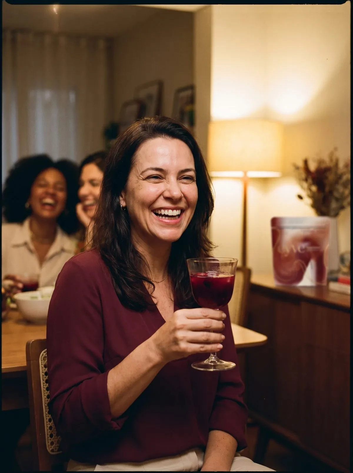 Mulher sorrindo brindando com uma taça de bebida de frutas vermelhas